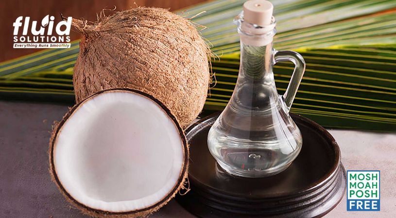 Coconut oil in glass bottle with fresh coconuts.