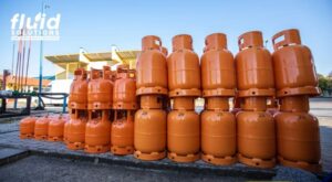 Stack of orange LPG gas cylinders outdoors.