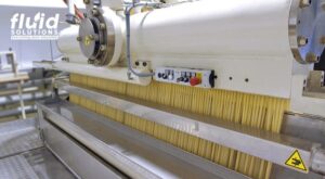 Industrial pasta-making machine extruding noodles.