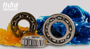 Three metallic bearings surrounded by yellow and blue industrial grease,