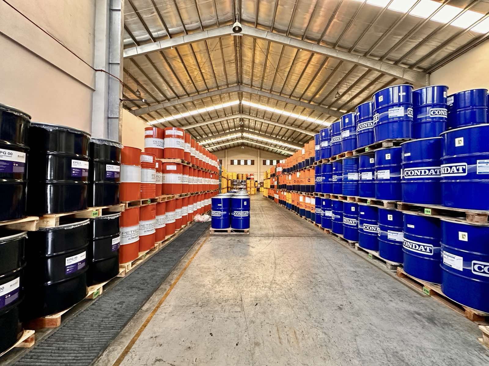 Warehouse with colorful industrial lubricant drums organized on pallets.