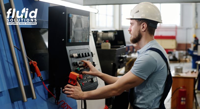 Worker operating CNC machine control panel.