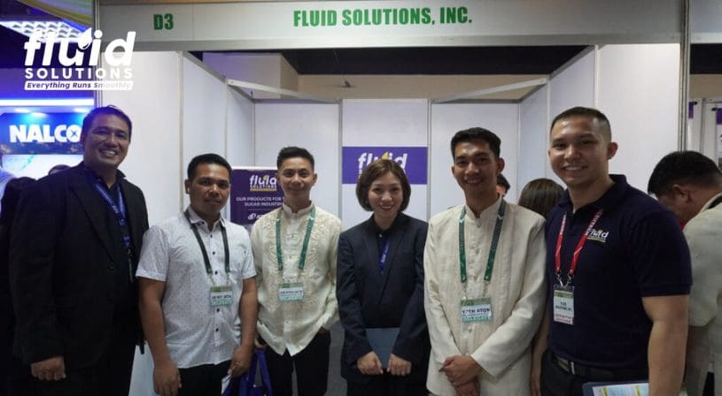 Fluid Solutions team and trade show attendees posing at the company's booth.