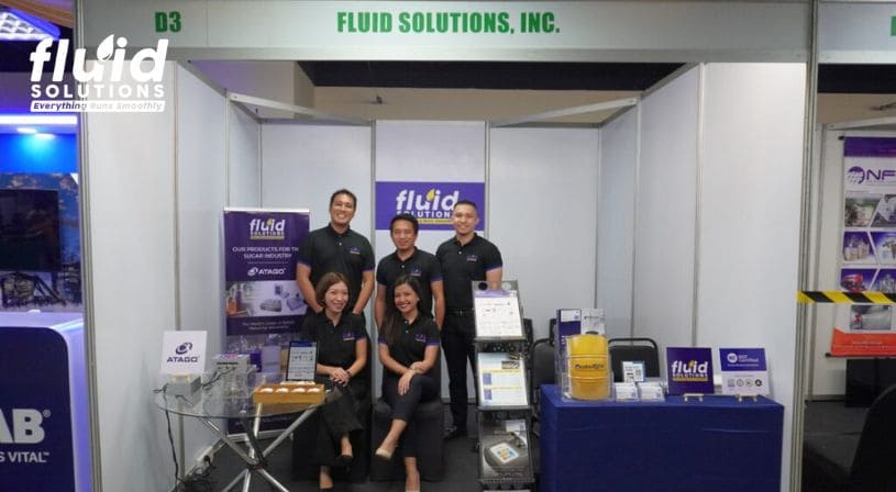 Fluid Solutions team at a trade show booth displaying products and promotional materials.