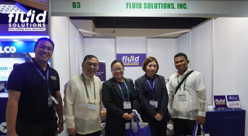 Group photo of Fluid Solutions team with event participants at their booth.