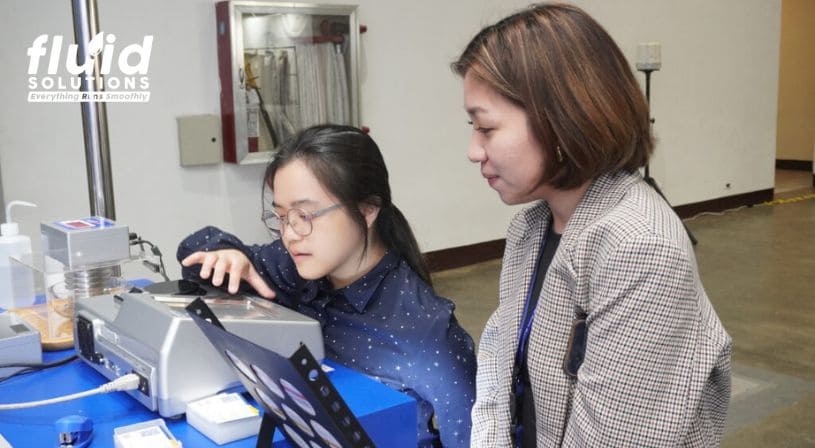 Two women examining equipment on display at the Fluid Solutions booth.