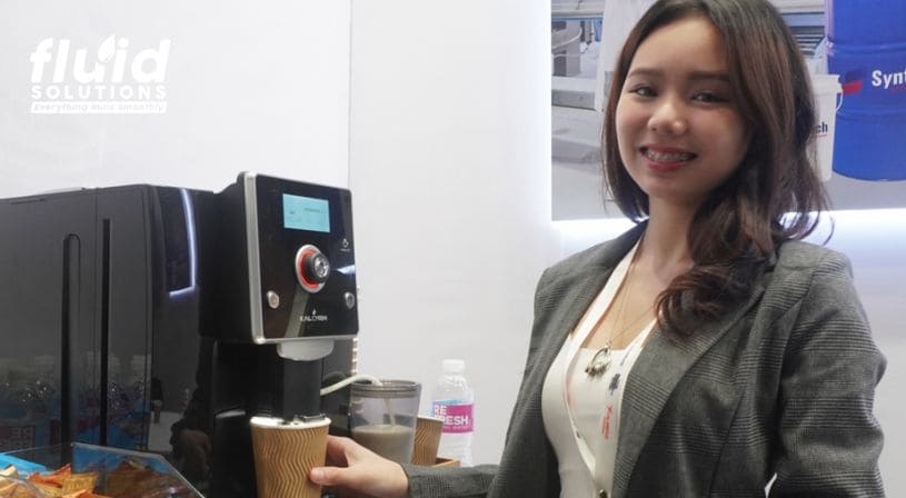 Fluid Solutions representative using a coffee machine at the trade show booth.