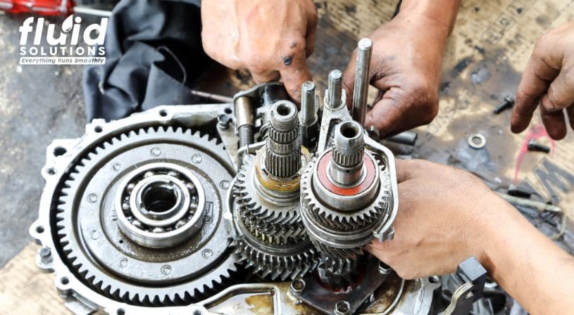 Hands working on a gearbox, showing mechanical assembly.