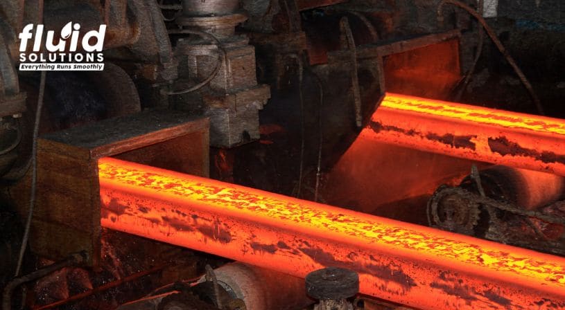 Red-hot metal rods being processed in an industrial machine.