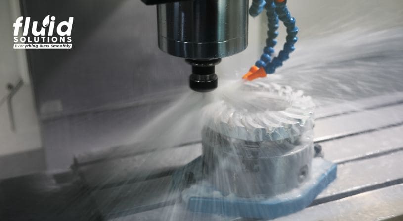 CNC machine spraying cooling fluid on metal part.