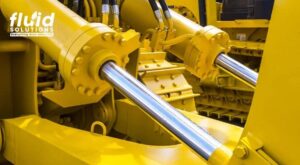 Close-up of hydraulic cylinders on yellow industrial machinery.