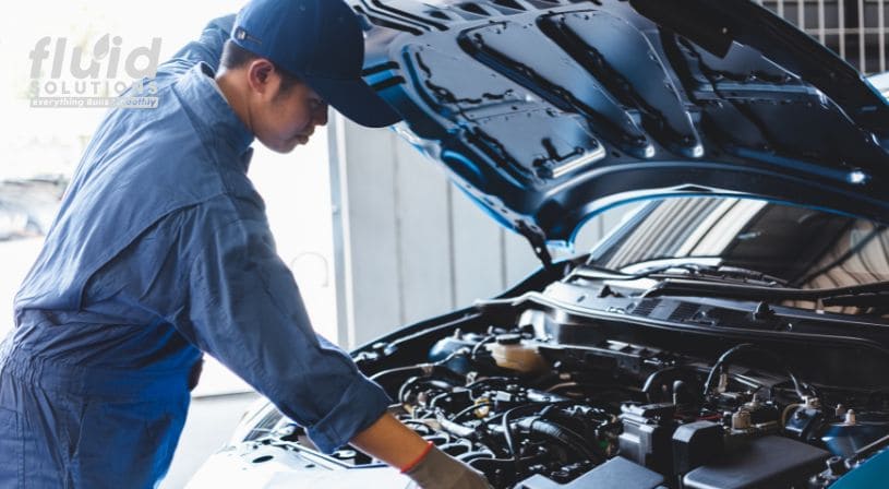 Mechanic inspecting a car engine under the hood.