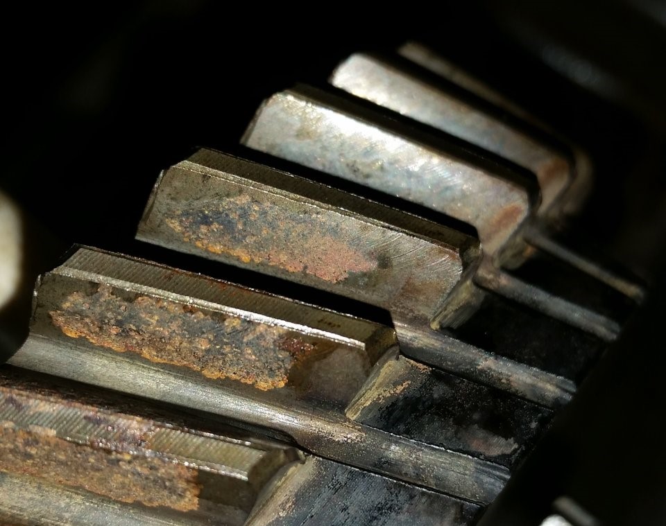 Close-up of rusted gear teeth showing corrosion and pitting.