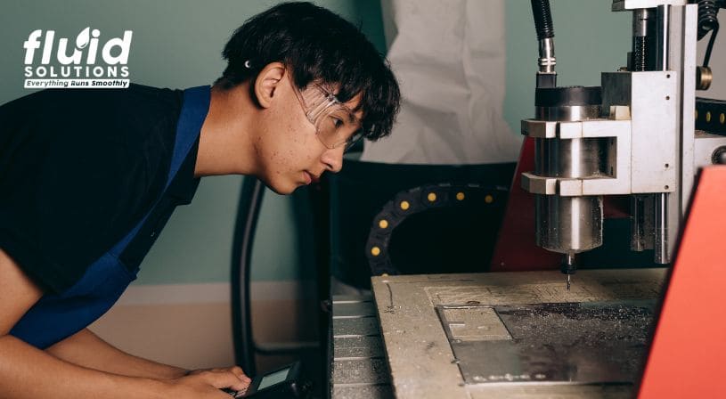 Technician inspecting a CNC machine in an industrial workshop.
