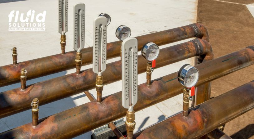 A collection of pipes featuring various thermometers, used for monitoring hydraulic fluid temperatures.