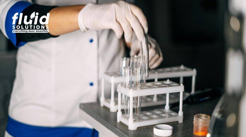 Laboratory technician performing lubricant quality testing using test tubes for industrial oil analysis and condition monitoring.